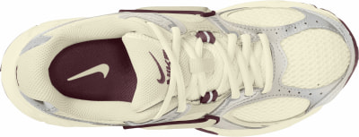 Cremefarbene Nike-Sneaker mit weinrotem Logo und Schnürsenkeln aus der Vogelperspektive. Cremefarbene Nike-Sneaker mit weinrotem Logo und Schnürsenkeln aus der Vogelperspektive.