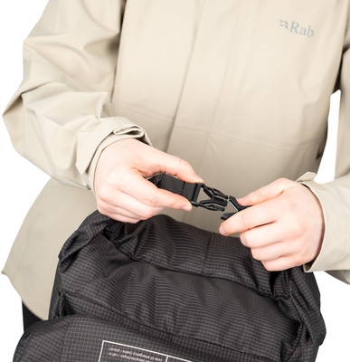 Osoba zapína pracku na čiernom batohu. Osoba zapína pracku na čiernom batohu.
