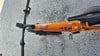 Orange E-Bike mit schwarzem Sattel und Lenker auf Schotter.