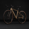 Ein braunes Gravelbike mit schwarzem Lenker und Sattel vor schwarzem Hintergrund.