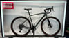 Graues Trek Gravelbike mit braunen Reifen auf einem Ständer.