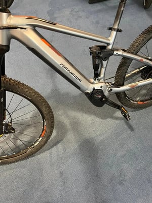 Silbernes Genesis E-Mountainbike mit orangefarbenen Details am Rahmen. Silbernes Genesis E-Mountainbike mit orangefarbenen Details am Rahmen.