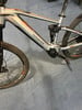 Silbernes Genesis E-Mountainbike mit orangefarbenen Details am Rahmen.