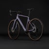 Lila Cube Gravelbike mit braunen Reifen vor schwarzem Hintergrund.