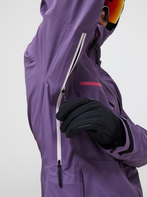 Detail einer lila Jacke mit schwarzer Handschuh und Reißverschluss. Detail einer lila Jacke mit schwarzer Handschuh und Reißverschluss.