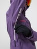 Detail einer lila Jacke mit schwarzer Handschuh und Reißverschluss.