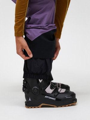 Detail eines Atomic-Skischuhs mit Hose und einer Hand, die den Saum anpasst. Detail eines Atomic-Skischuhs mit Hose und einer Hand, die den Saum anpasst.