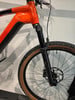 Vorderseite eines orangefarbenen Mountainbikes mit Federgabel und Felge.