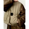 Eine Person hält eine beige gesteppte Weste über einer braunen gesteppten Jacke.