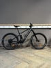 Ein schwarzes Scott E-Mountainbike steht auf einem Holzboden vor einer grauen Wand.