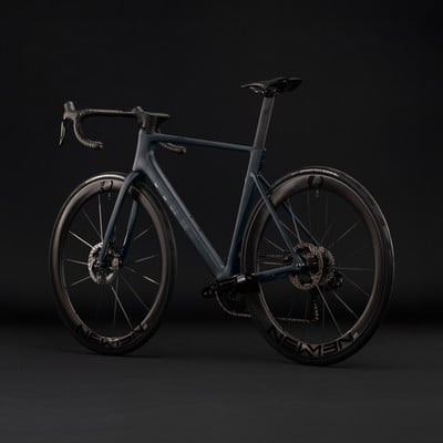 Ein dunkelblaues Rennrad mit Carbonfelgen auf schwarzem Hintergrund.