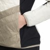Detail einer Jacke mit Hand in der Tasche, beige und schwarze Einsätze.