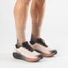 Beige Laufschuhe von Salomon mit rosa und schwarzen Details und Socken.