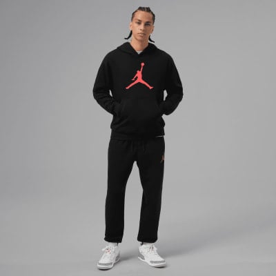 Ein Mann in schwarzer Kleidung mit Jumpman-Logo posiert vor grauem Hintergrund. Ein Mann in schwarzer Kleidung mit Jumpman-Logo posiert vor grauem Hintergrund.