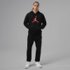 Ein Mann in schwarzer Kleidung mit Jumpman-Logo posiert vor grauem Hintergrund.