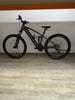 Ein graues E-Mountainbike mit Federung steht auf Holzboden.