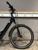 Vorderansicht eines dunkelblauen E-Bikes mit Federgabel und Scheibenbremse.