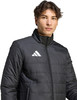 Ein Mann in einer schwarzen Steppjacke mit Adidas-Logo auf der Brust.