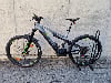 Ein Genesis E-Mountainbike mit Federung und Schutzblechen steht auf Pflastersteinen.