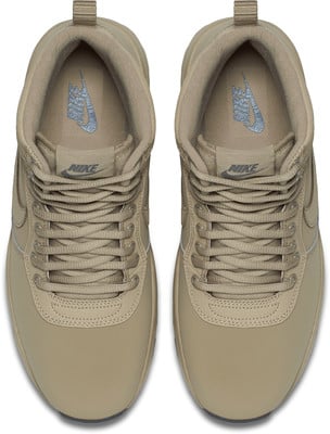 Draufsicht auf beige Nike-Sneaker mit Schnürung und Logos. Draufsicht auf beige Nike-Sneaker mit Schnürung und Logos.