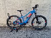 Ein blaues Mountain-E-Bike steht auf einem Ständer vor einer Betonwand.