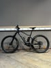 Ein schwarzes Scott Mountain E-Bike mit Federung steht auf einem Holzboden.