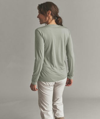 Eine Frau in einem grünen Langarmshirt und heller Hose steht mit dem Rücken zur Kamera. Eine Frau in einem grünen Langarmshirt und heller Hose steht mit dem Rücken zur Kamera.