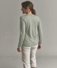 Eine Frau in einem grünen Langarmshirt und heller Hose steht mit dem Rücken zur Kamera.