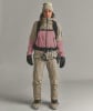 Eine Frau in einer Skijacke, Hose und Skischuhen mit Gurt.