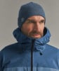 Mann in blauer Winterjacke und Mütze mit Logo.