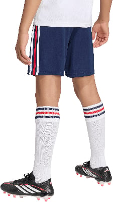 Kind in dunkelblauen Shorts mit Streifen, weißen Socken und schwarzen Fußballschuhen.