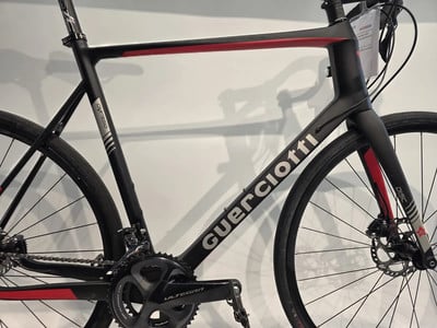 Ein schwarzes Carbon-Rennrad mit roten Akzenten und Guerciotti-Schriftzug. Ein schwarzes Carbon-Rennrad mit roten Akzenten und Guerciotti-Schriftzug.