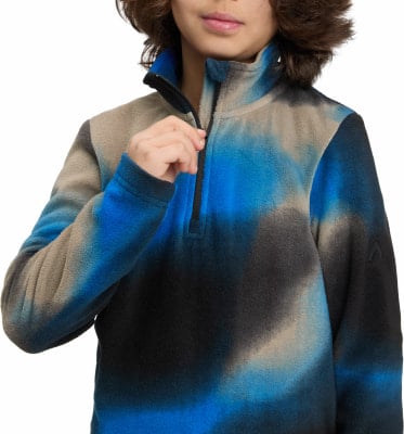 Dítě si zapíná modro-béžovou fleecovou bundu s tie-dye vzorem. Dítě si zapíná modro-béžovou fleecovou bundu s tie-dye vzorem.