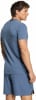 Ein Mann in einem blauen T-Shirt und Shorts blickt über die Schulter.