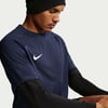 Ein Mann in einem dunkelblauen T-Shirt mit weißem Nike-Logo und schwarzer Mütze.