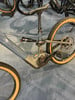 Detail eines E-Mountainbikes mit Dämpfer, Bosch-Motor und orangefarbenen Reifen.