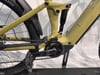 Detail der Rückseite eines gelben E-Bikes mit Dämpfer und Pedalen.
