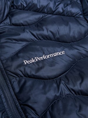 Detail einer dunkelblauen Daunenjacke mit Peak Performance Logo.
