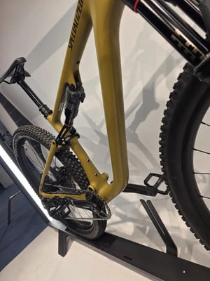 Ein goldenes Mountainbike mit Federung auf einem Ständer, Nahaufnahme des Hinterbaus. Ein goldenes Mountainbike mit Federung auf einem Ständer, Nahaufnahme des Hinterbaus.