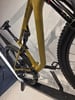 Ein goldenes Mountainbike mit Federung auf einem Ständer, Nahaufnahme des Hinterbaus.
