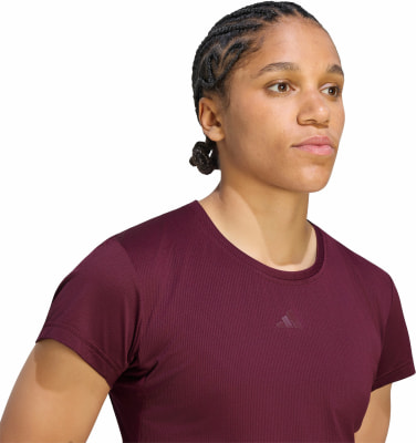 Frau in einem dunkelburgunderfarbenen kurzärmeligen T-Shirt mit Adidas-Logo. Frau in einem dunkelburgunderfarbenen kurzärmeligen T-Shirt mit Adidas-Logo.