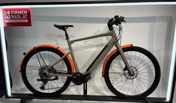 Modernes E-Bike in Grau mit orangen Schutzblechen und Firmenlogo.