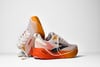 Zwei Brooks-Laufschuhe mit orange-weißer Sohle.