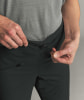 Detail eines Mannes, der die Kordel am Bund einer schwarzen Hose zuzieht.