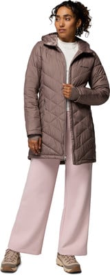 Eine Frau in einer gesteppten Jacke und rosa Hose posiert vor weißem Hintergrund. Eine Frau in einer gesteppten Jacke und rosa Hose posiert vor weißem Hintergrund.