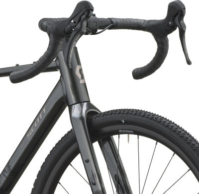 Detail des Vorderteils eines dunkelgrauen Gravelbikes mit Lenker und Rad. Detail des Vorderteils eines dunkelgrauen Gravelbikes mit Lenker und Rad.