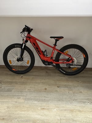 Ein orangefarbenes KTM-Mountainbike mit dicken Reifen auf Holzboden. Ein orangefarbenes KTM-Mountainbike mit dicken Reifen auf Holzboden.