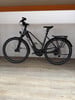 Ein schwarzes KTM E-Bike mit Gepäckträger und Licht steht auf dem Boden.
