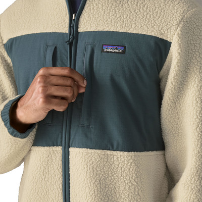 Detail einer Patagonia-Jacke mit Logo und Reißverschluss, beige und dunkelblau. Detail einer Patagonia-Jacke mit Logo und Reißverschluss, beige und dunkelblau.