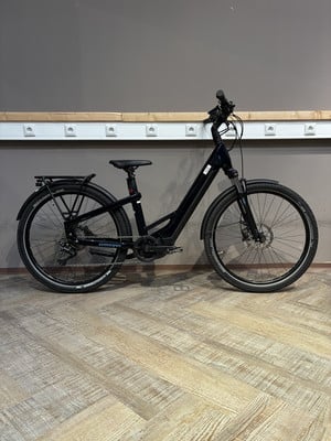 Schwarzes E-Bike mit Gepäckträger und Schutzblechen auf Holzboden. Schwarzes E-Bike mit Gepäckträger und Schutzblechen auf Holzboden.